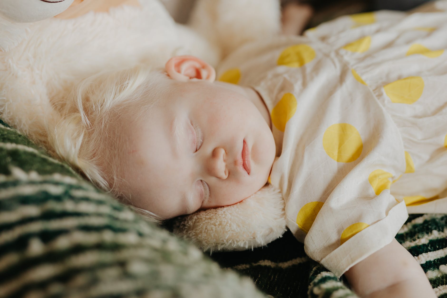 baby in white and yellow polka dot dress sleeping